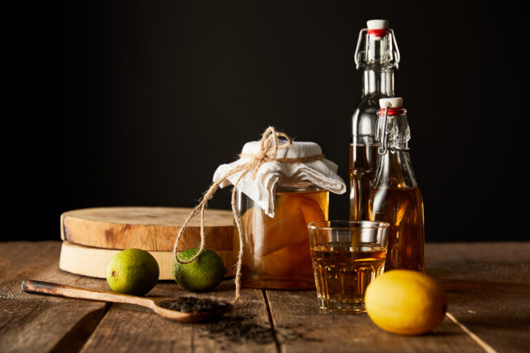 glass jar with kombucha near lime, lemon, and spices