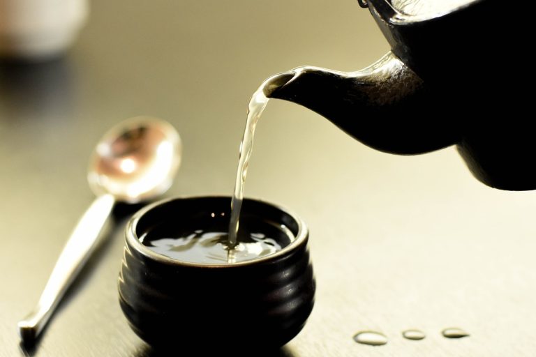 pouring tea from a teapot with a spoon next to it