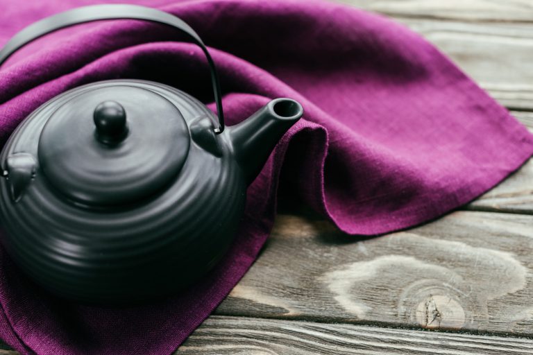 Metal teapot on purple cloth