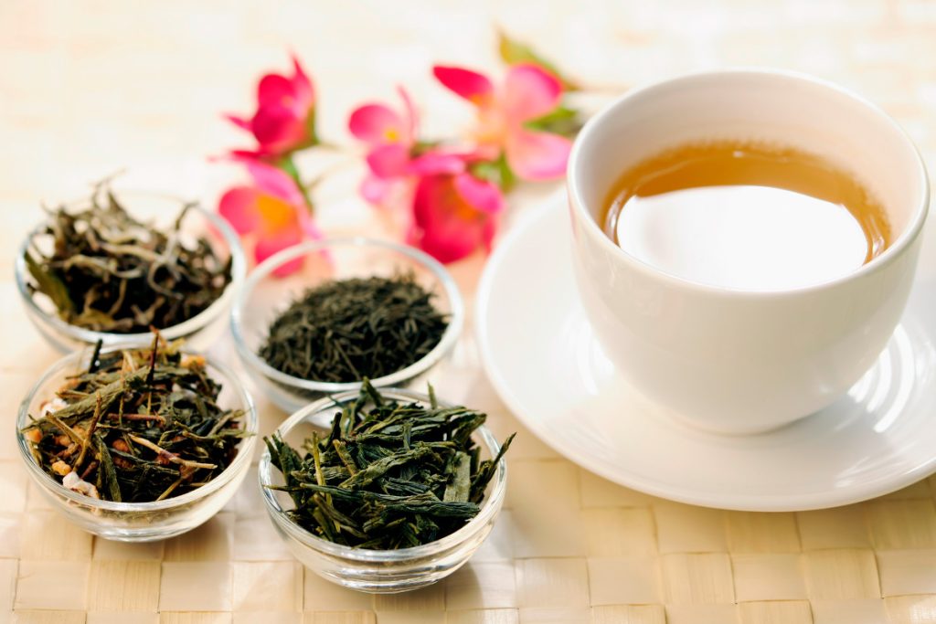 different types of green tea next to a teacup