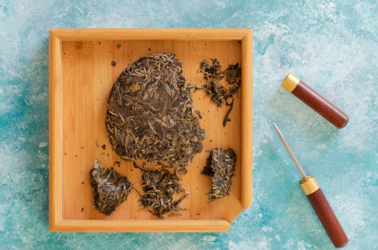 Pressed puer tea on wooden stand and tea knife
