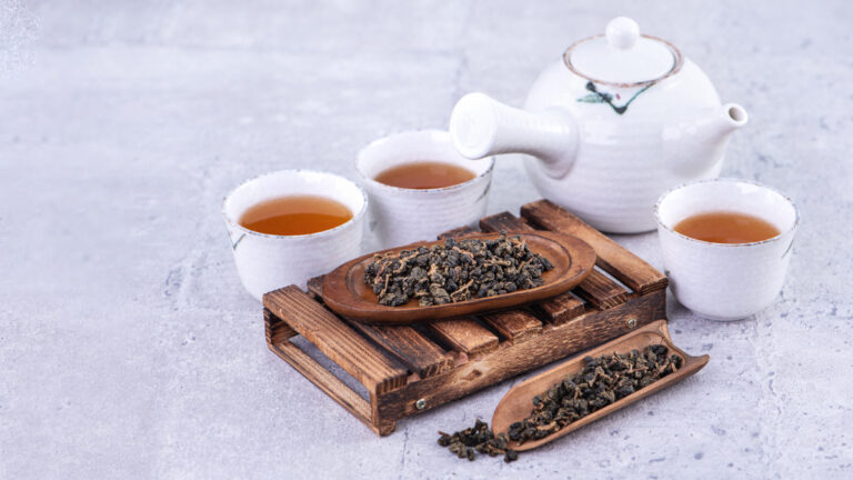 hot tea in white teapot and cups on gray cement background