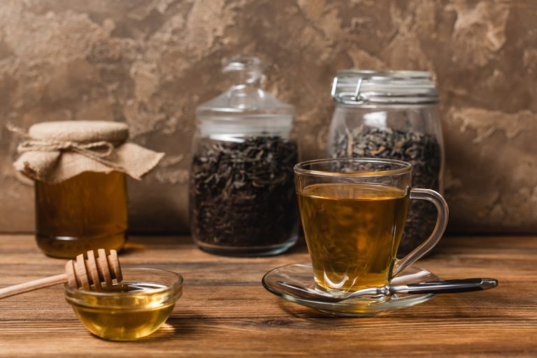 Cup of tea near honey and blurred jars
