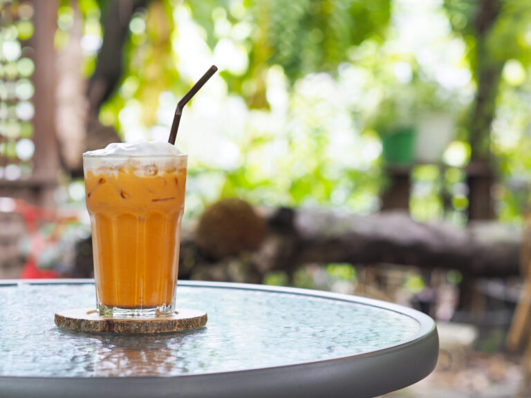 Glass of Thai milk tea with whipped cream on top and straw