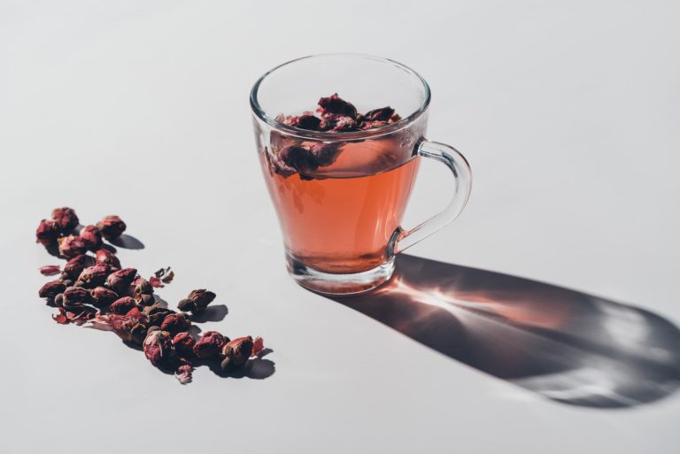 Red tea of dried roses in cup on white tabletop
