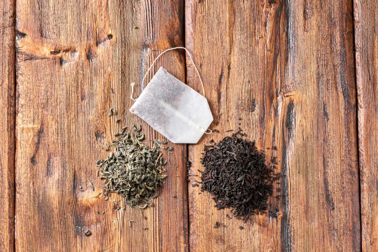 green and black tea next to a tea bag on wooden background