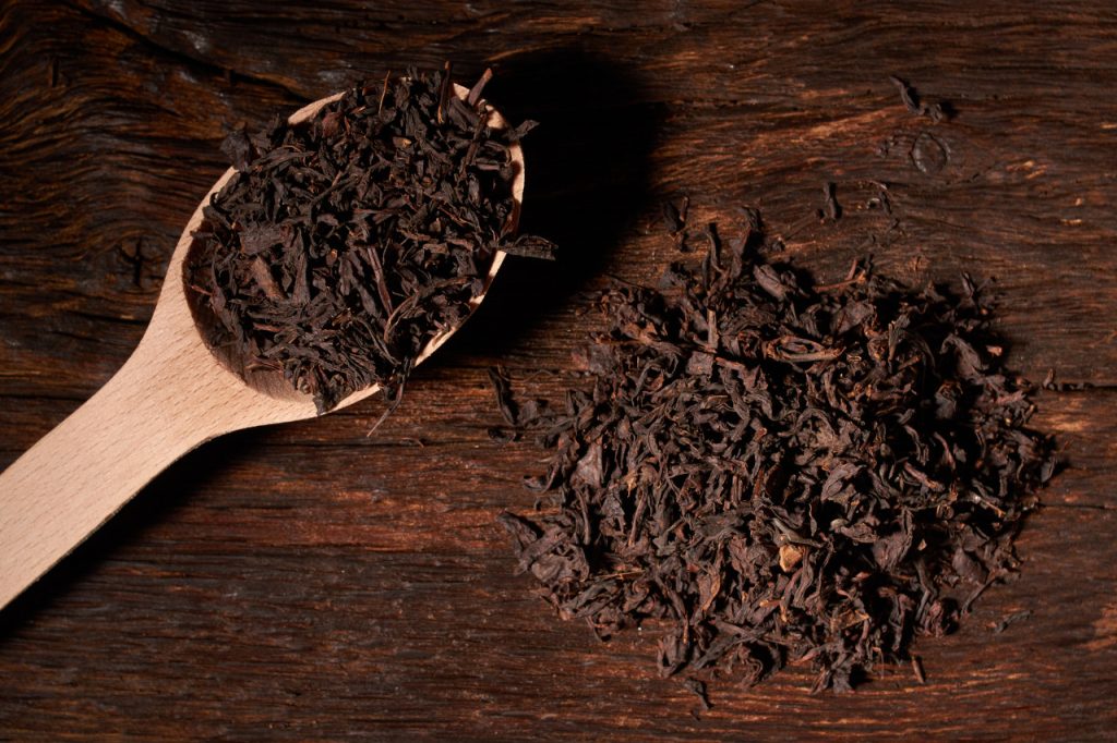 black tea in wooden spoon on dark wooden table