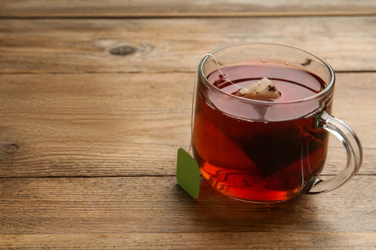 Tea bag in a glass cup of hot water on a wooden table