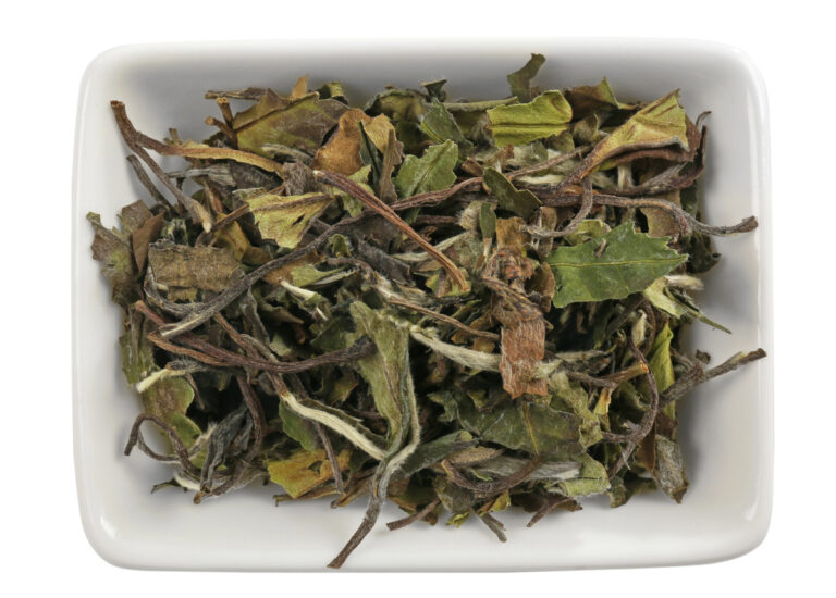 white tea leaves in a bowl on white background